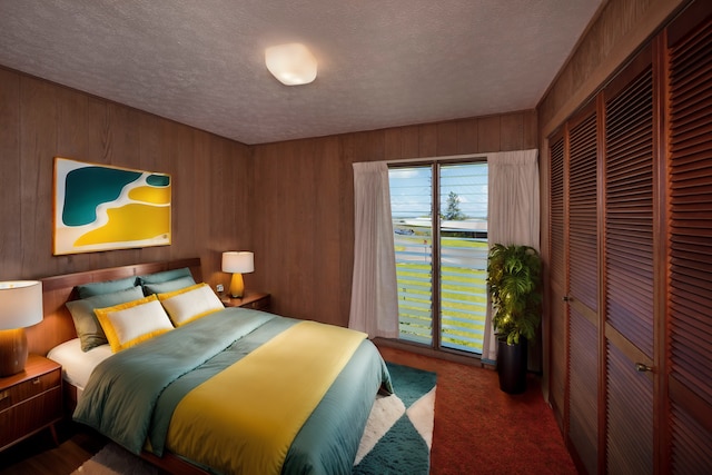 bedroom with a textured ceiling, a closet, carpet, and wooden walls