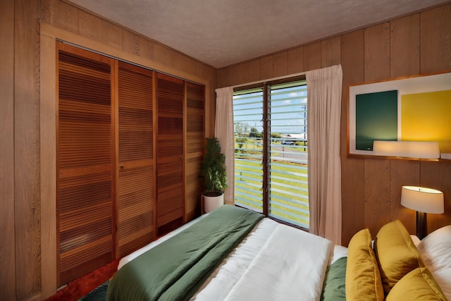 bedroom with a closet, wooden walls, and a textured ceiling