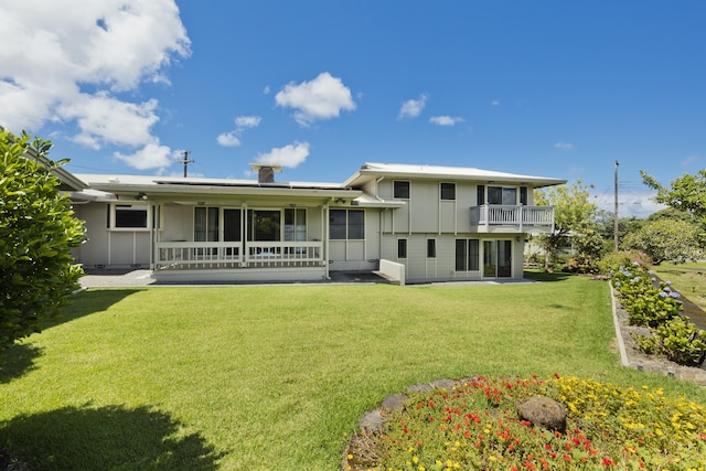 rear view of property featuring a balcony and a lawn