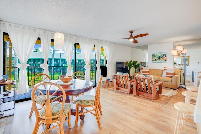 dining room with light wood-type flooring, a textured ceiling, and ceiling fan