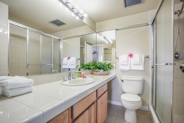 bathroom with toilet, vanity, tile patterned floors, and a shower with shower door