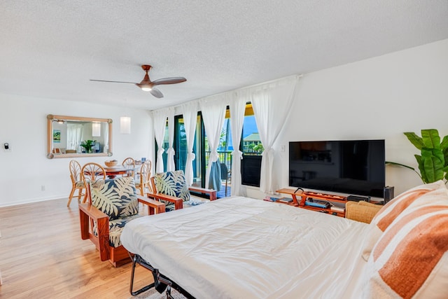 bedroom featuring access to exterior, ceiling fan, light hardwood / wood-style floors, and a textured ceiling