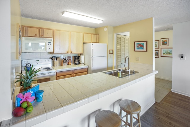 kitchen with sink, tile countertops, a textured ceiling, white appliances, and light brown cabinetry