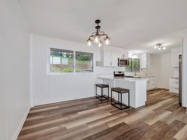 kitchen featuring a healthy amount of sunlight, white cabinetry, kitchen peninsula, and stainless steel appliances