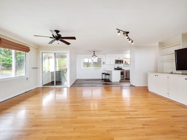 unfurnished living room with ceiling fan, light wood-type flooring, and rail lighting