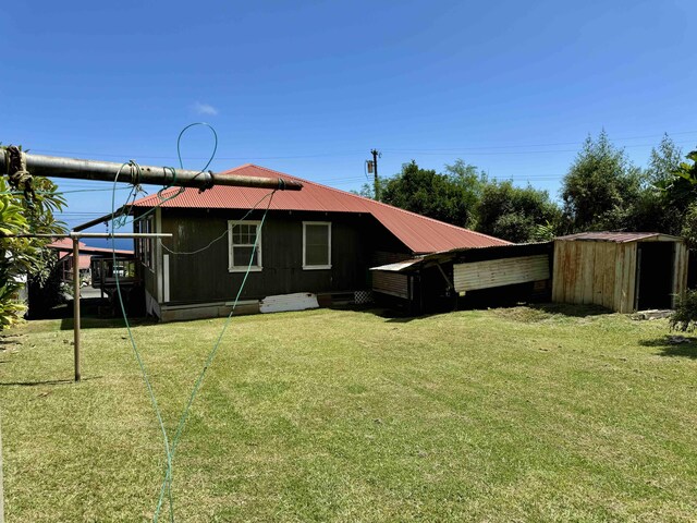 back of property featuring a yard and a storage unit