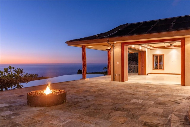 patio terrace at dusk featuring a fire pit and a water view