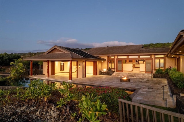 back house at dusk featuring a patio