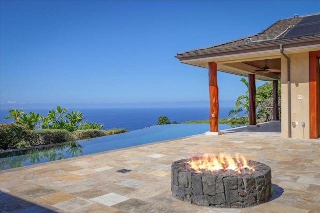 view of patio / terrace featuring a water view, an outdoor fire pit, and ceiling fan