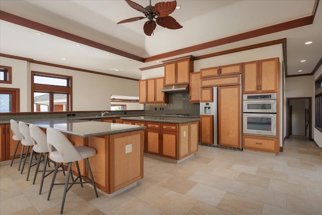 kitchen with paneled refrigerator, backsplash, ceiling fan, double oven, and a kitchen island