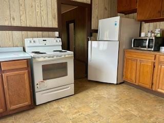 kitchen with white appliances and wood walls