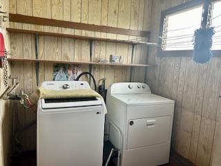 clothes washing area with wood walls, laundry area, and washing machine and clothes dryer