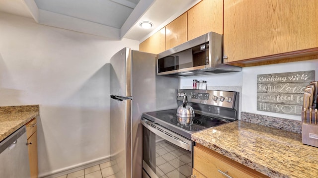 kitchen with light tile patterned flooring, light stone counters, and stainless steel appliances