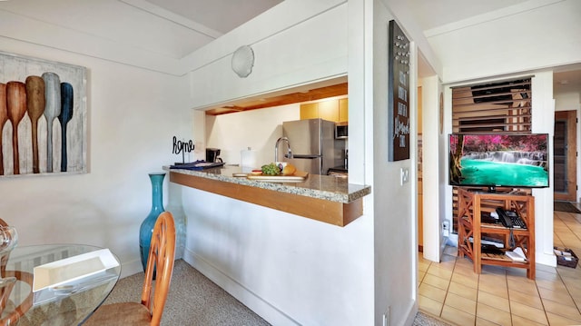 interior space featuring appliances with stainless steel finishes, stone countertops, and light tile patterned floors