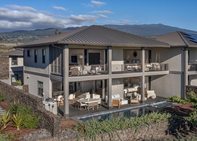 rear view of property featuring outdoor lounge area, a mountain view, a balcony, and a patio area