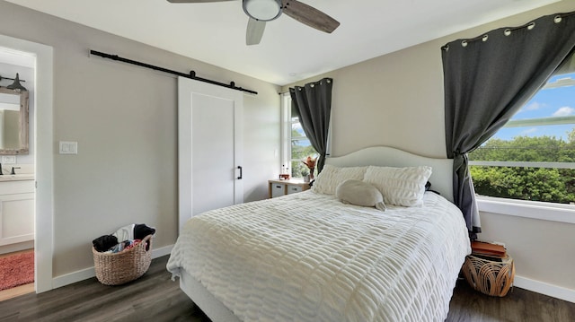 bedroom with a barn door, dark wood-type flooring, and multiple windows