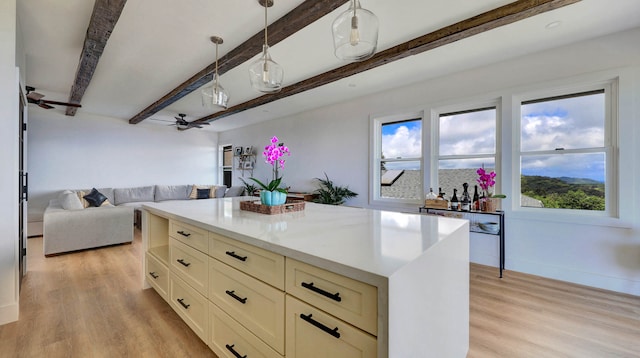 kitchen featuring hanging light fixtures, beamed ceiling, ceiling fan, and light hardwood / wood-style floors