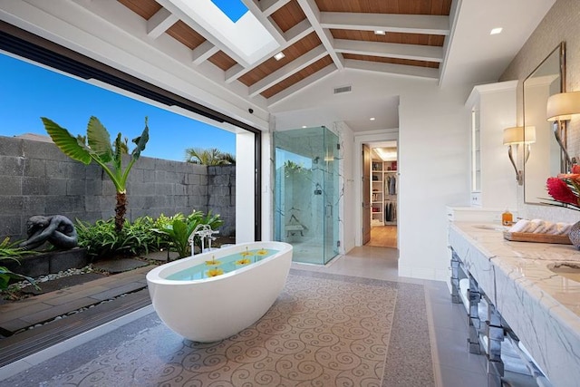 bathroom featuring double vanity, tile walls, tile patterned floors, vaulted ceiling with skylight, and plus walk in shower