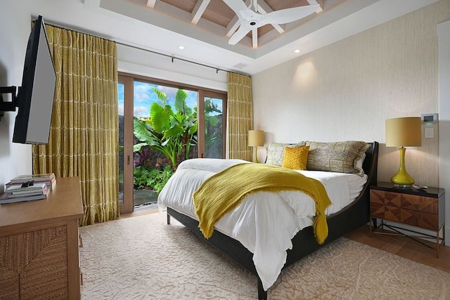 bedroom featuring ceiling fan, access to exterior, and a tray ceiling