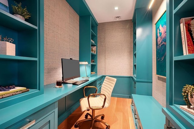 office space featuring hardwood / wood-style flooring, built in shelves, and built in desk