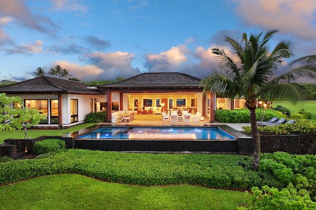 pool at dusk featuring a patio and a yard