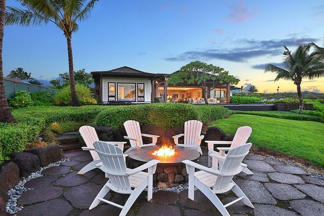 patio terrace at dusk featuring a yard and a fire pit