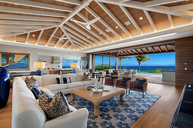 living room featuring beam ceiling, wood-type flooring, a water view, and high vaulted ceiling