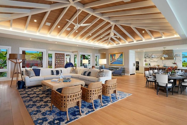 living room featuring light hardwood / wood-style floors, high vaulted ceiling, ceiling fan, and beamed ceiling