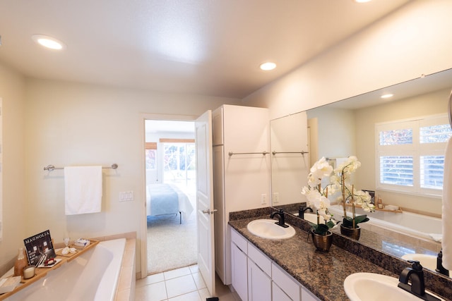 bathroom featuring tile patterned floors, vanity, and tiled bath