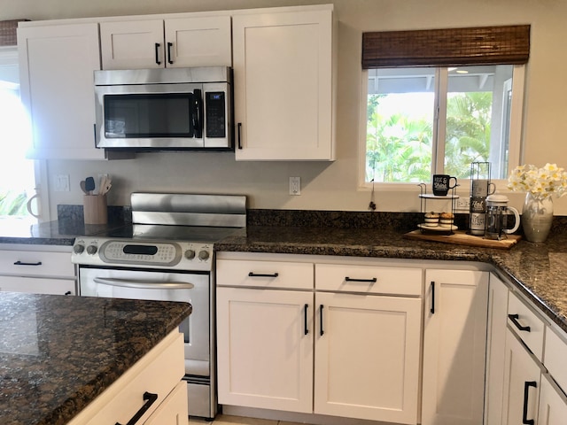 kitchen with white cabinets, stainless steel appliances, and dark stone counters