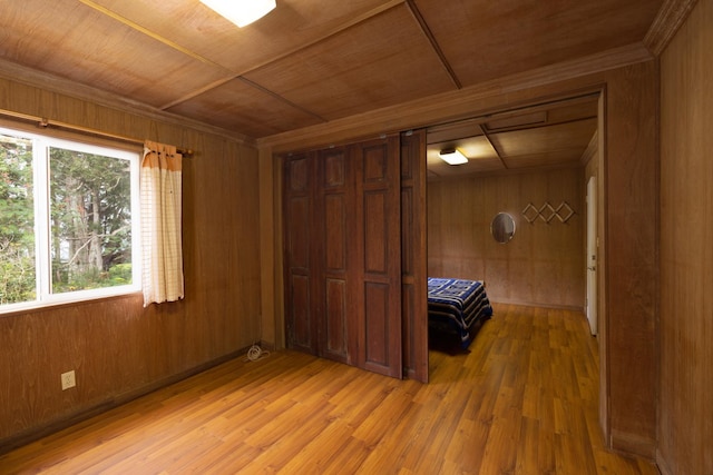 unfurnished bedroom with wood walls, wooden ceiling, and light hardwood / wood-style flooring