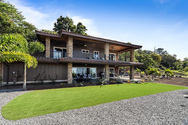 back of property with a lawn, ceiling fan, and a balcony