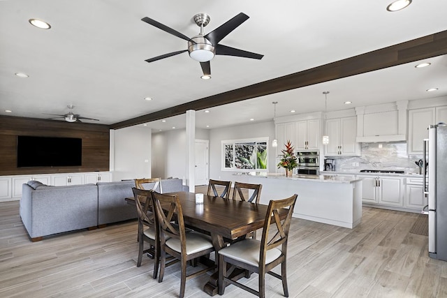 dining space featuring beamed ceiling, light hardwood / wood-style floors, and ceiling fan