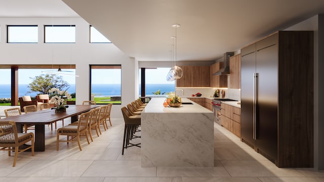 kitchen with wall chimney exhaust hood, a water view, high quality appliances, a kitchen island, and pendant lighting