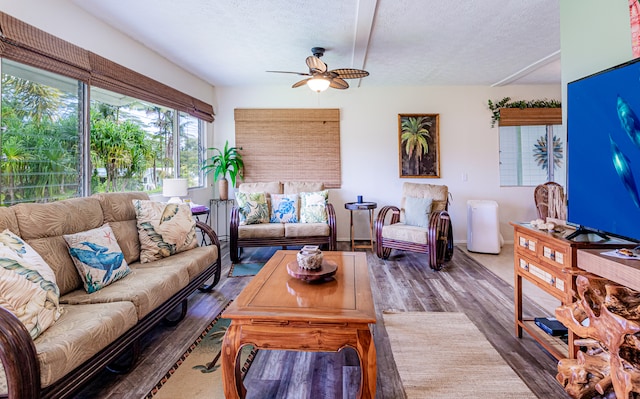 living room featuring hardwood / wood-style flooring, ceiling fan, and a textured ceiling