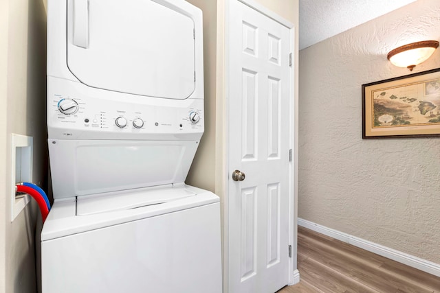 washroom with hardwood / wood-style flooring and stacked washer and dryer