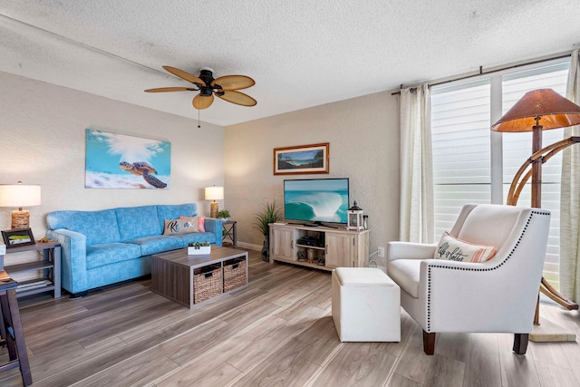 living room with a textured ceiling, wood-type flooring, and ceiling fan