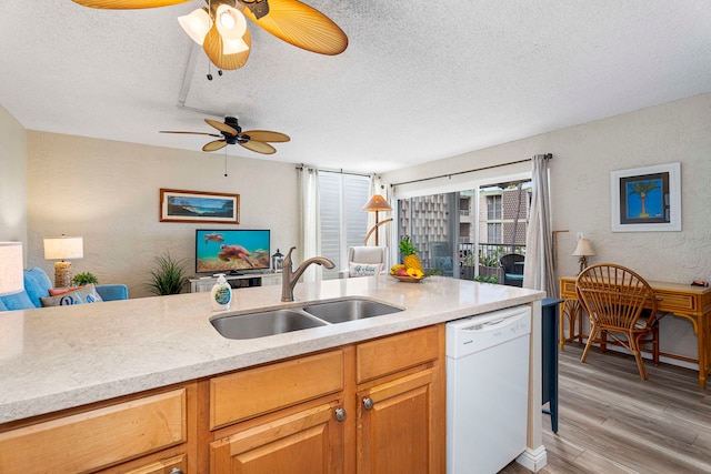 kitchen featuring light hardwood / wood-style flooring, dishwasher, ceiling fan, sink, and a textured ceiling