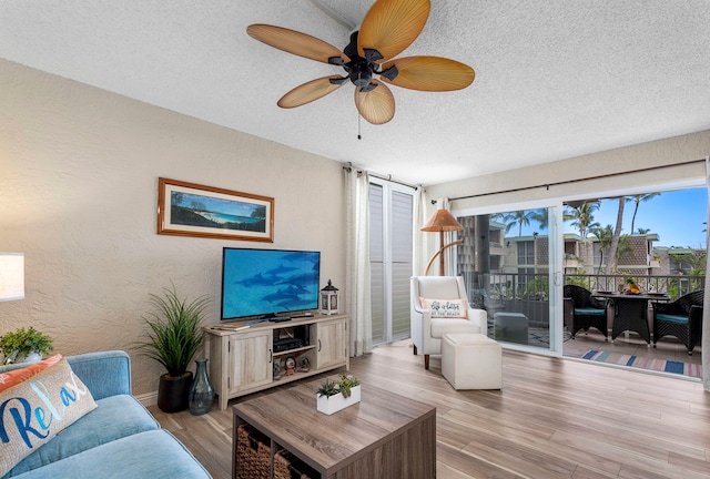 living room featuring ceiling fan, light hardwood / wood-style floors, and a textured ceiling