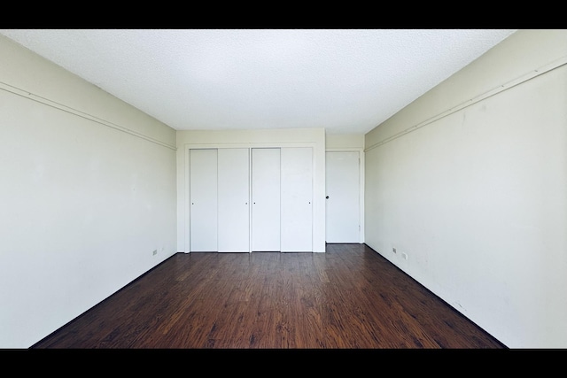 unfurnished bedroom featuring a textured ceiling and dark hardwood / wood-style flooring