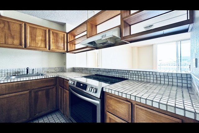 kitchen featuring tile countertops, sink, electric stove, and ventilation hood