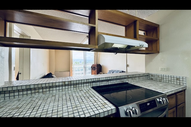 interior details with stainless steel range with electric stovetop and tile counters