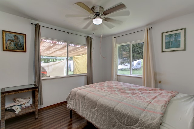 bedroom featuring dark wood-type flooring, ceiling fan, and multiple windows