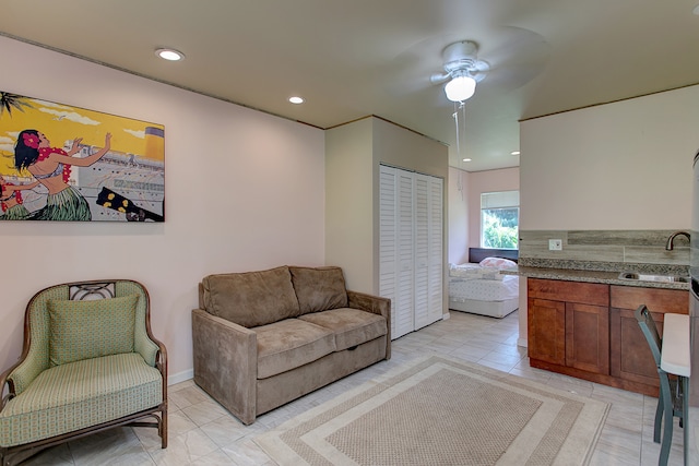 living room featuring ceiling fan, sink, and light tile floors