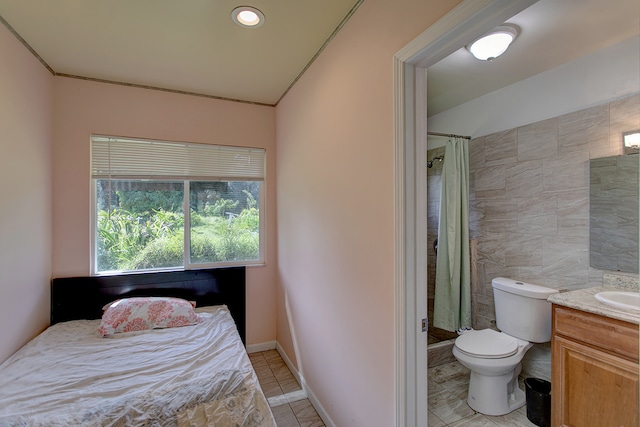 interior space featuring tile walls, toilet, tile flooring, walk in shower, and vanity