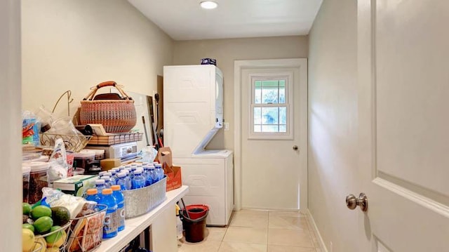 clothes washing area featuring light tile patterned floors and stacked washer and clothes dryer