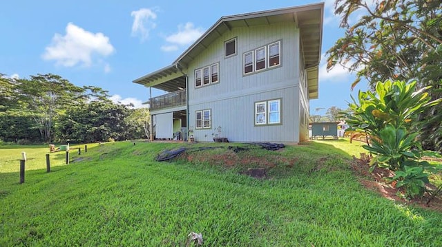 rear view of house with a lawn and a balcony