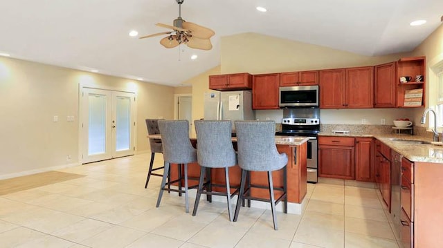 kitchen with sink, vaulted ceiling, ceiling fan, light tile patterned flooring, and stainless steel appliances