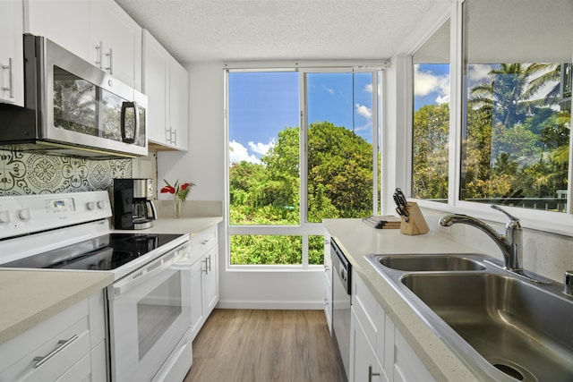 kitchen with white cabinetry, sink, a textured ceiling, appliances with stainless steel finishes, and light wood-type flooring