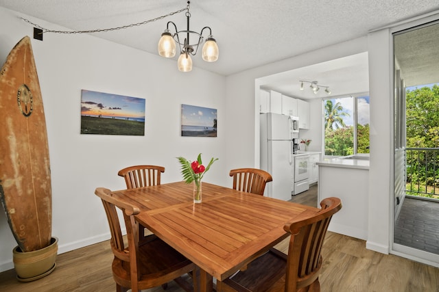 dining space with a textured ceiling, wood finished floors, and baseboards